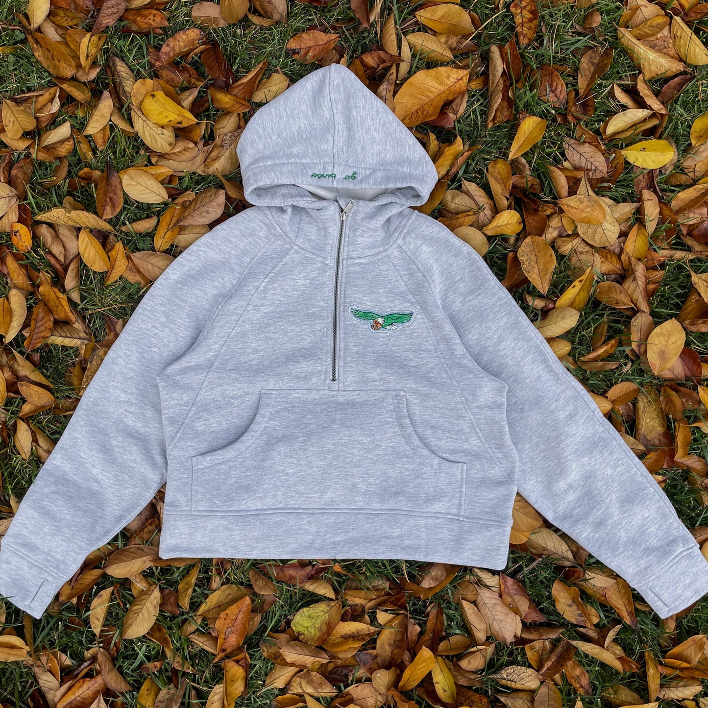 Gray hoodie with a logo on a bed of autumn leaves