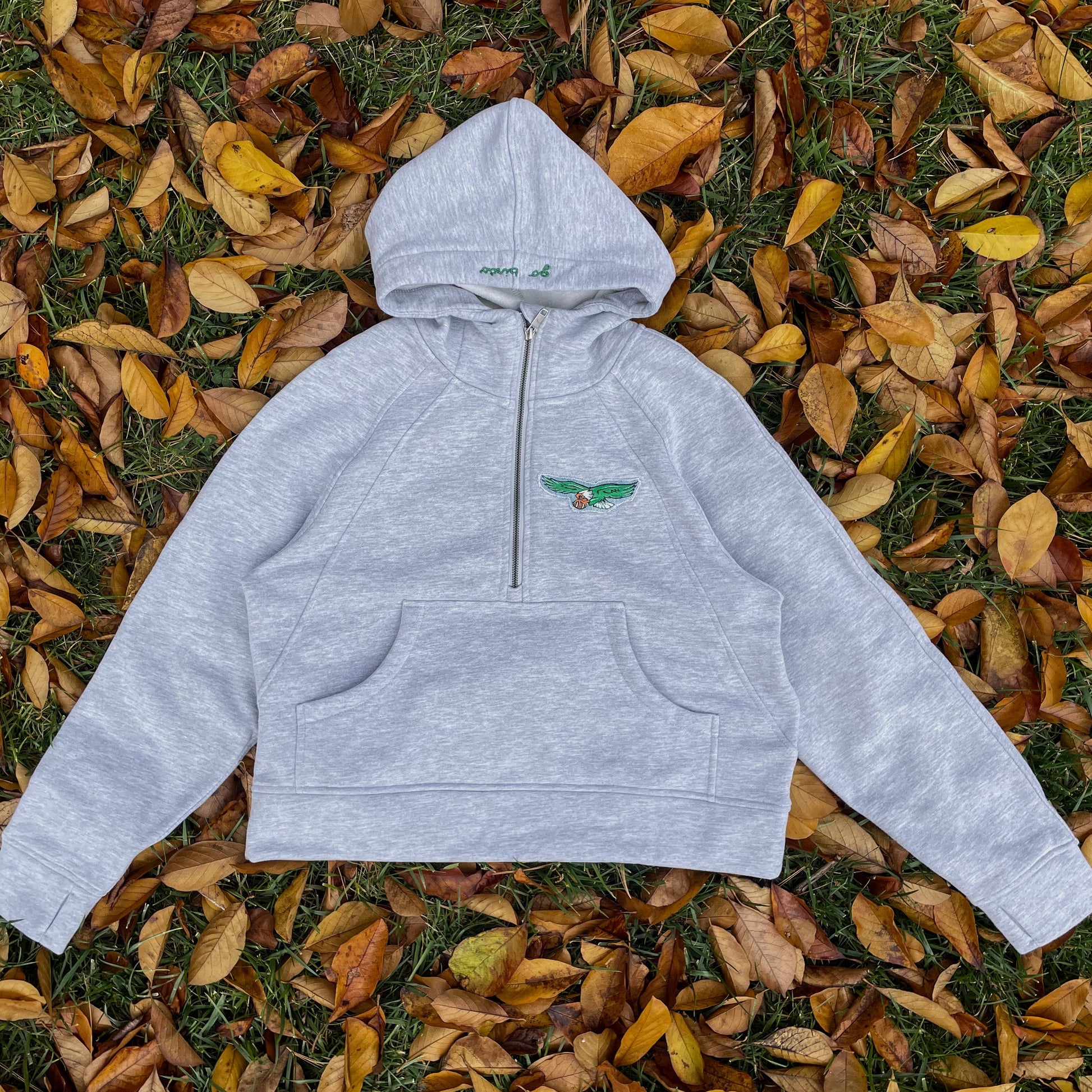 Gray hoodie with a logo on a bed of autumn leaves